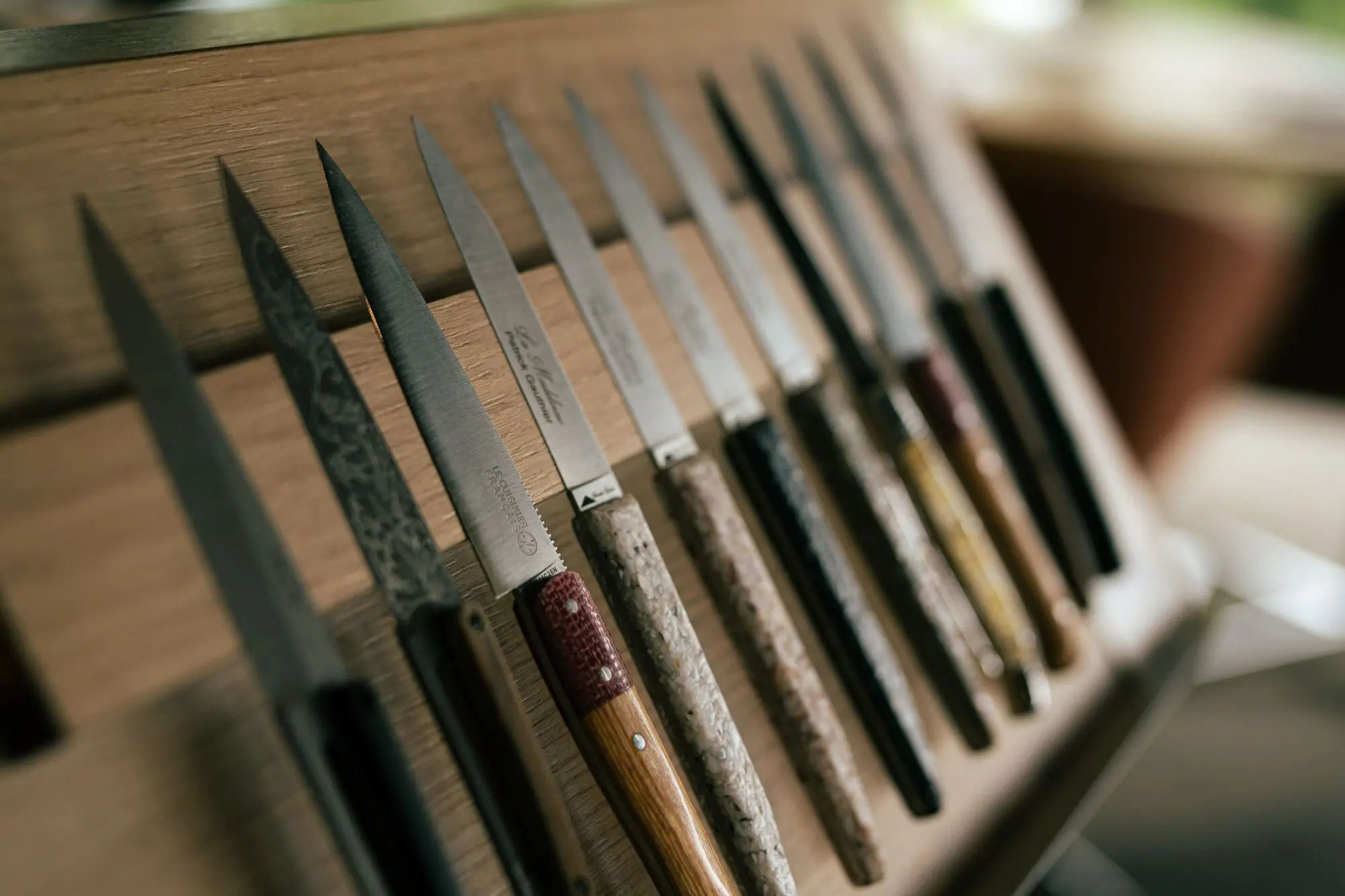 Couteaux de table aux manches variés, alignés sur une planche en bois – La Madeleine, restaurant gastronomique à Sens