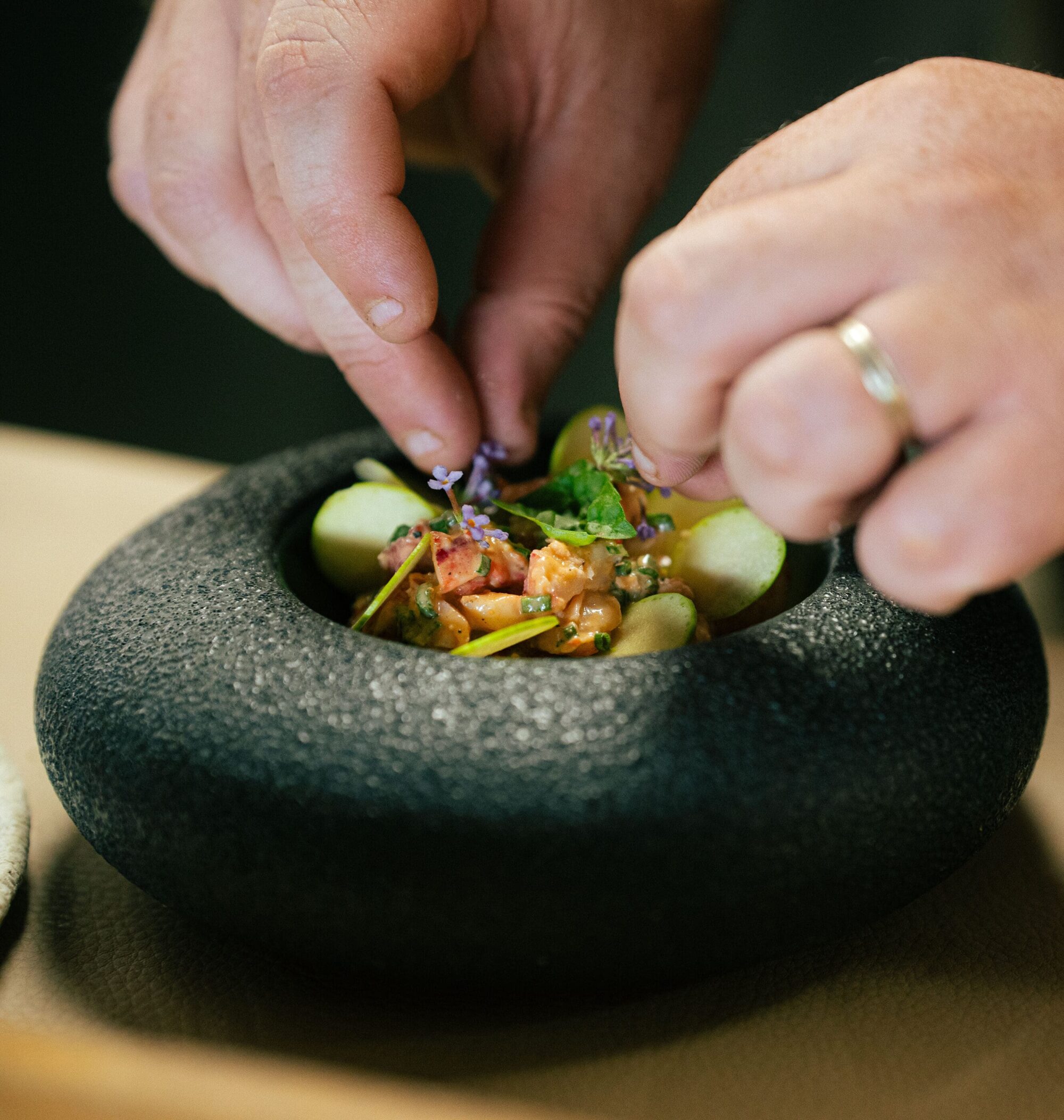 Dressage minutieux d'un plat dans un bol de pierre noire – cuisine de Patrick Gauthier, restaurant étoilé à Sens