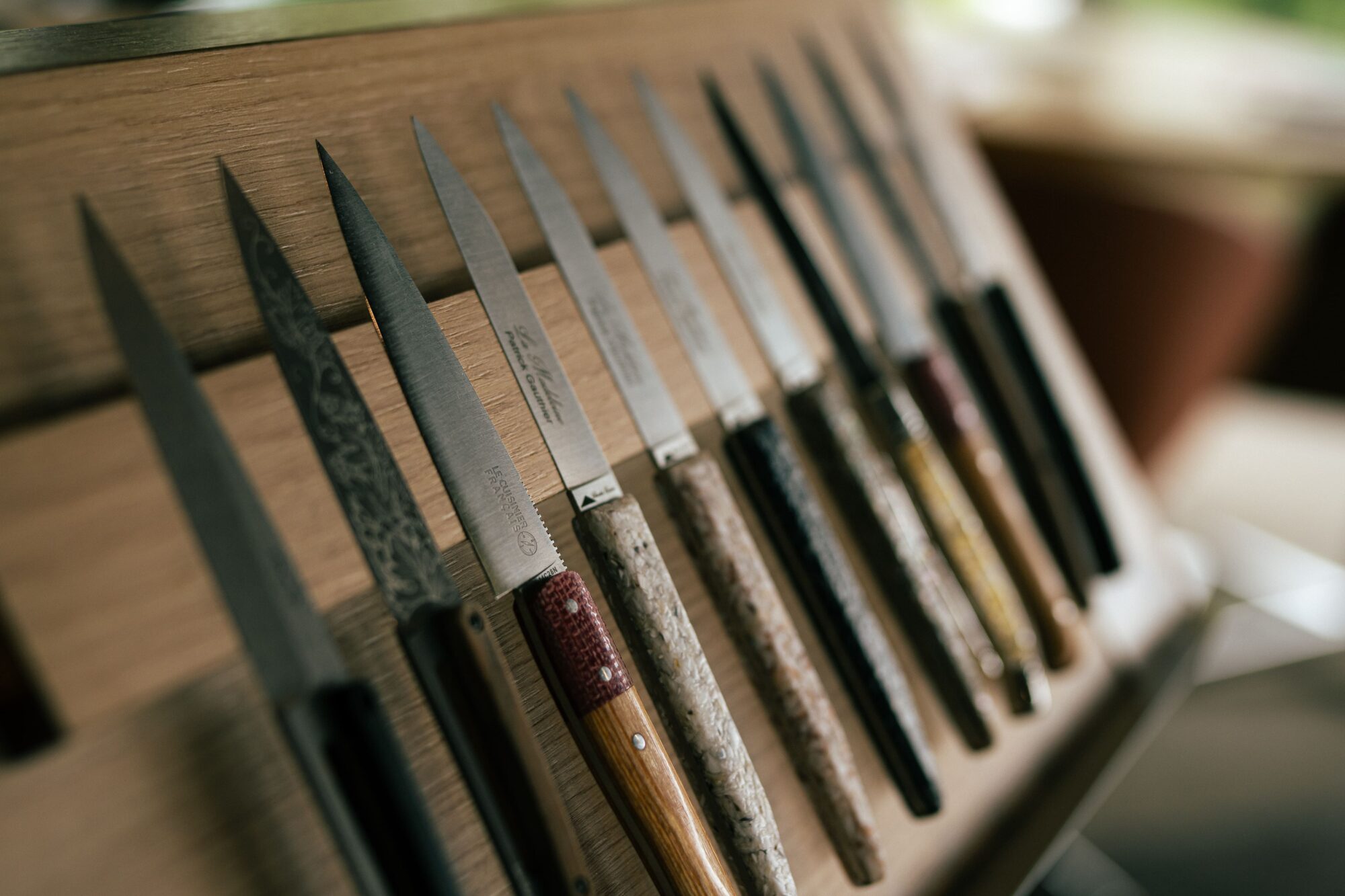 Couteaux de table aux manches variés, alignés sur une planche en bois – La Madeleine, restaurant gastronomique à Sens