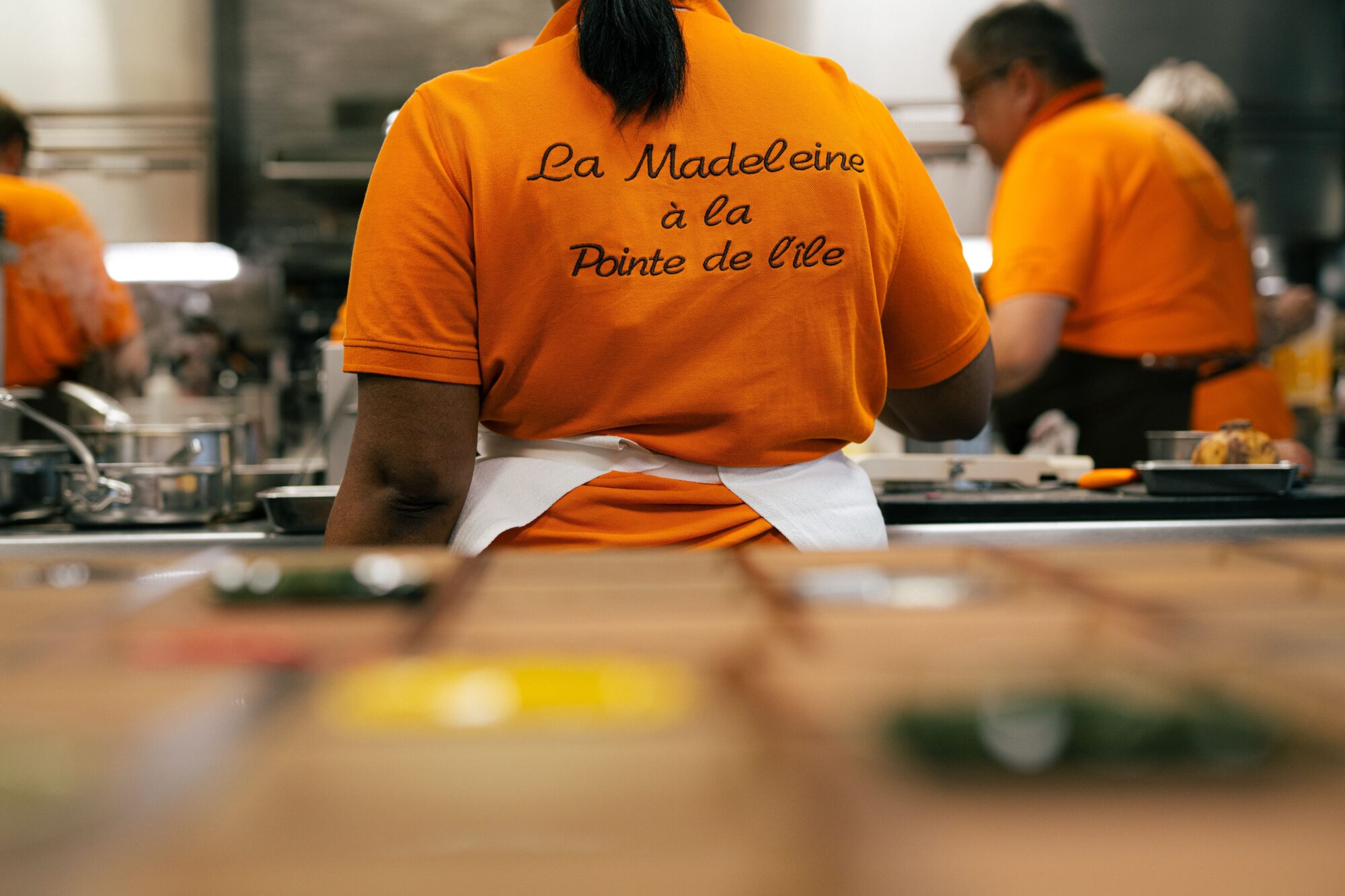 Cuisinier de La Madeleine de dos, en cuisine ouverte